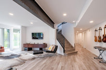 Load image into Gallery viewer, Modern living room with staircase, TV, and guitars on the wall. Space for rent in Edmonton area
